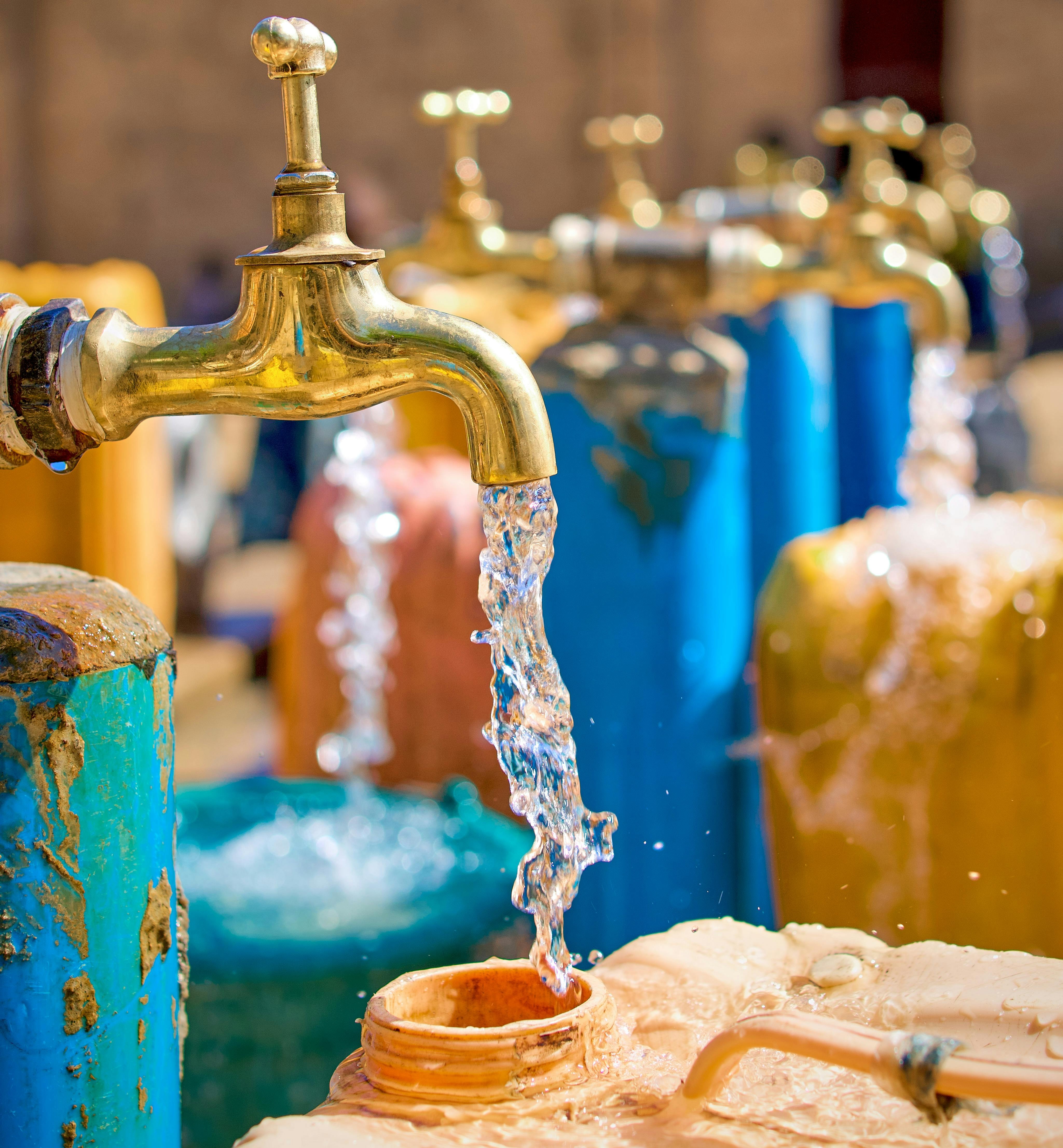 water spigot on flowing water into an orange plastic bucket