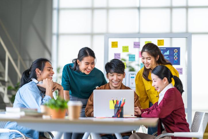 Group of people sitting and smiling at a computer